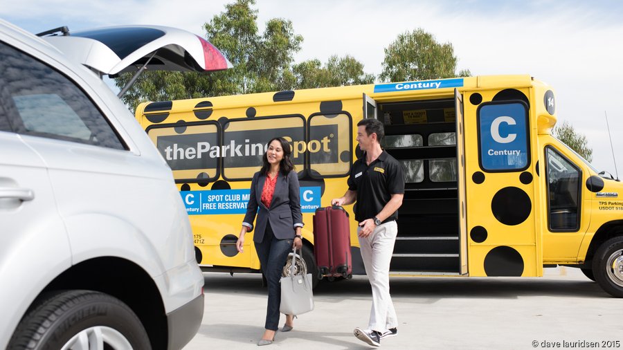 Parking Spot shuttle bus parked at a secure airport lot with passengers boarding.