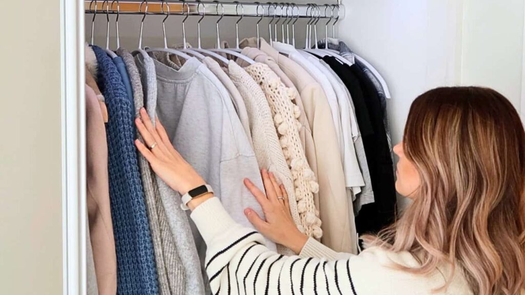 A flat lay showing a neutral blazer, white tee, high-waisted trousers, classic jeans, a black slip dress, and a collection of simple yet impactful accessories like a gold chain necklace and a structured belt.